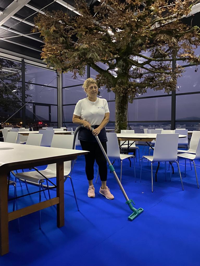 Mitarbeiterin wischt den Boden in einem Eventraum