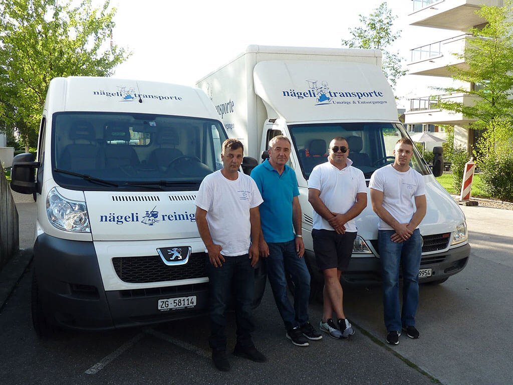 Vier Mitarbeiter von nägeli transporte vor den Firmenfahrzeugen